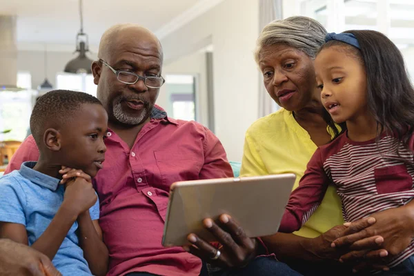 多种族祖父母 孙子孙女坐在家里观看数字平板电脑上的视频 无线技术 不变的家庭 童年和退休概念 — 图库照片