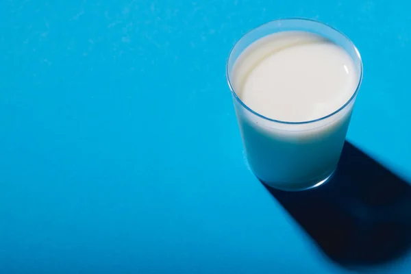 コピースペースのある青の背景にミルクのガラスの高い角度ビュー 変更されていない 食べ物 飲み物 スタジオで撮影された健康的な食品コンセプト — ストック写真