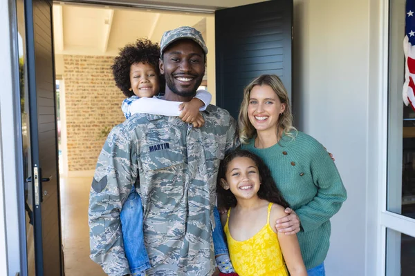 一个快乐的多种族士兵的画像 她带着妇女和儿童站在屋门口 不变的家庭 爱国主义和归国观念 — 图库照片