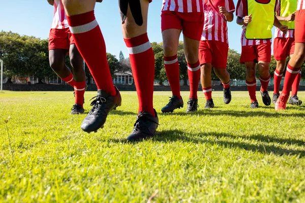 stock image Low section of male multiracial players wearing red socks and black shoes running on grassy field. Playground, unaltered, soccer, sport, teamwork, competition, exercising, training and fitness.