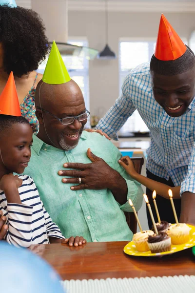 多种族老年人头戴派对帽 和家人一起庆祝生日时看着蛋糕 甜蜜的食物 享受和家庭观念 — 图库照片