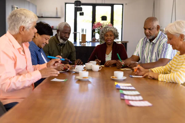 Multiraciální Starší Přátelé Hrají Bingo Při Kávě Sušenky Jídelního Stolu — Stock fotografie