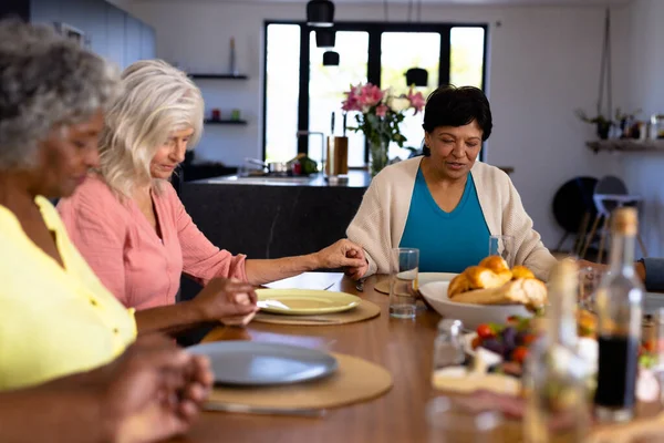 在养老院 多种族的资深女性朋友手牵着手 在餐桌前说着优雅的话 辅助生活和退休 — 图库照片