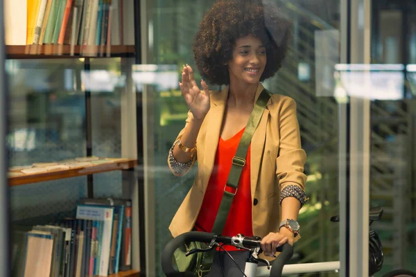 自転車の笑顔と現代のオフィスで手を振ってアフリカ系アメリカ人女性 ビジネスやオフィスのコンセプト — ストック写真