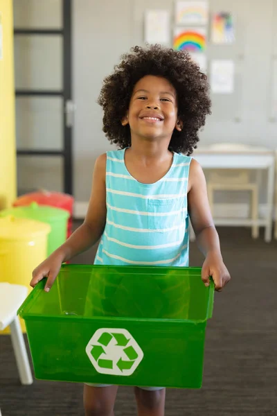 一个面带微笑的非洲裔美国小学生拿着装有回收符号的容器的画像 环境清理 可持续生活方式和学校概念 — 图库照片