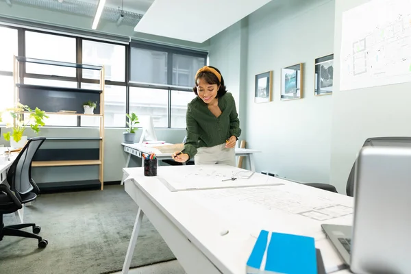 アジアの若い女性建築家が創造的なオフィスのテーブルで青写真を作っています 変更されていない 創造的なビジネス デザインの専門家 フロアプラン — ストック写真