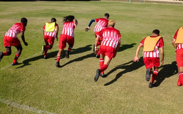 身穿红色球衣的男性运动员在操场上草地上奔跑时的高视角画面 团队合作 训练和健身等概念 — 图库照片
