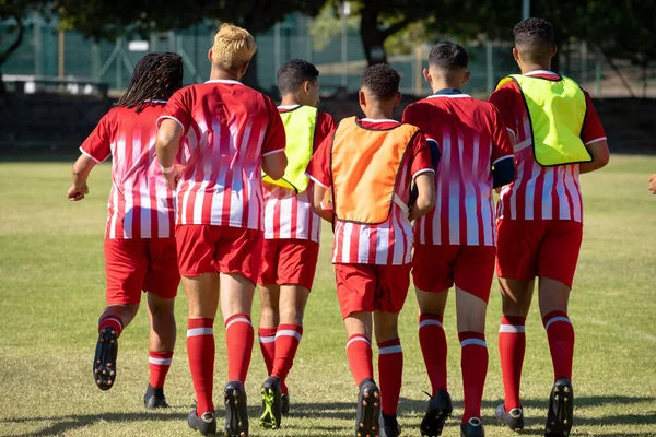 Achteraanzicht Van Multiraciale Mannelijke Voetballers Rode Sportuniformen Speelplaats Ongewijzigd Voetbal — Stockfoto