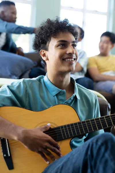 Leende Ung Man Spelar Gitarr Medan Multiracial Manliga Vänner Koppla — Stockfoto