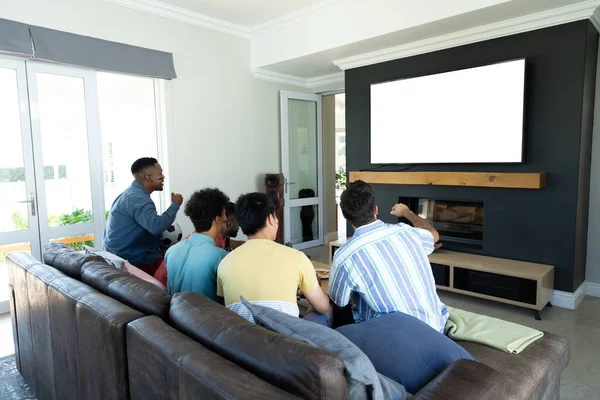 Πολυφυλετικές Αρσενικό Φίλους Βλέποντας Τηλεόραση Ενώ Χαλαρώνοντας Στον Καναπέ Στο — Φωτογραφία Αρχείου