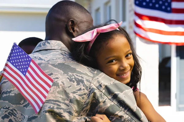 stock image Portrait of happy multiracial girl with flag of america embracing army soldier father in yard. Unaltered, family, togetherness, childhood, happy, military, patriotism, homecoming.
