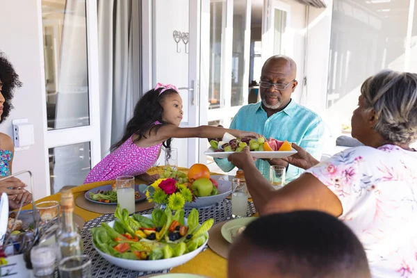 Abuelos Multirraciales Sirviendo Frutas Nieta Mientras Almuerzan Mesa Comedor Casa —  Fotos de Stock