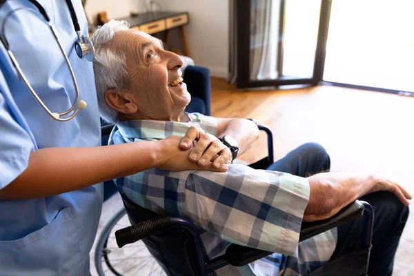 車椅子に座る白人シニア男性を支える女性保健従事者の中間部 医療と定年退職シニアライフスタイルの概念 — ストック写真