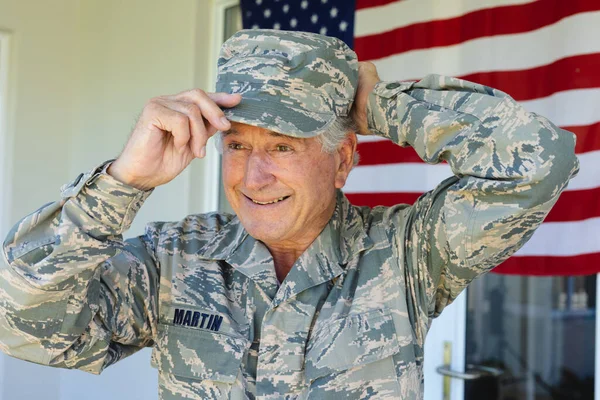 Uśmiechnięty Starszy Żołnierz Armii Białej Kamuflażu Noszący Czapkę Przeciwko Fladze — Zdjęcie stockowe