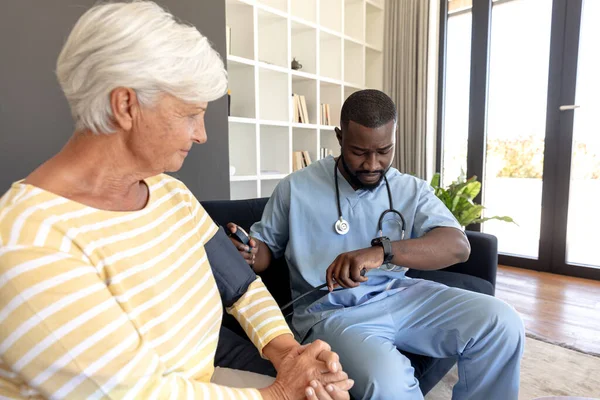 아프리카 미국인 집에서 코카서스 여성의 혈압을 확인하고 있습니다 서비스와 노인의 — 스톡 사진