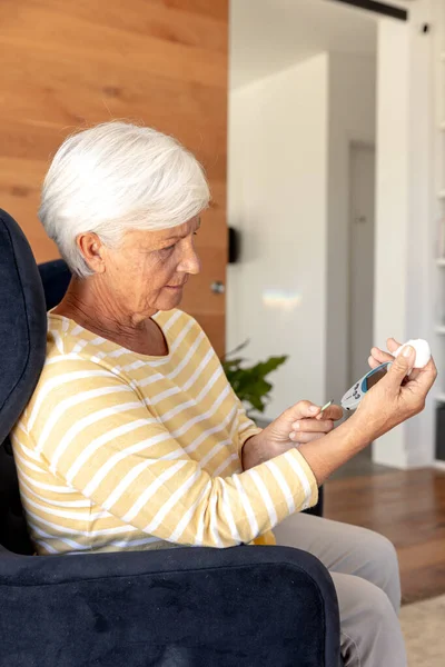 自宅で血糖値を測定する白人のシニア女性 医療と定年退職シニアライフスタイルの概念 — ストック写真
