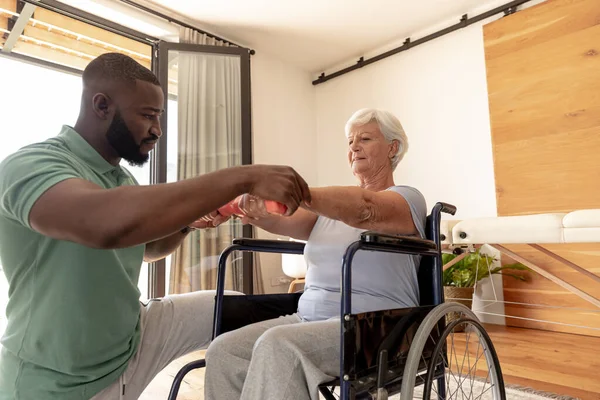 Afrika Kökenli Amerikalı Erkek Fizyoterapist Beyaz Yaşlı Kadının Halterlerle Egzersiz — Stok fotoğraf