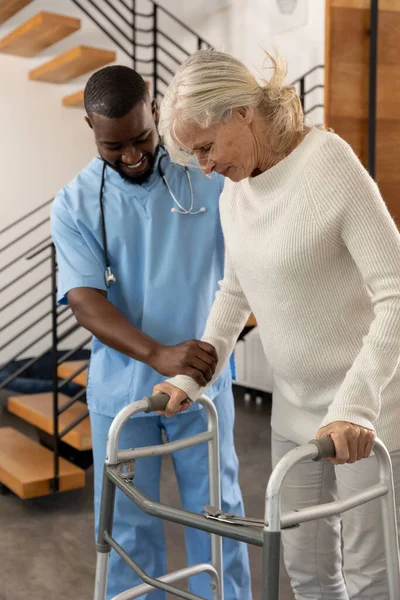 Африканский Американский Медицинский Работник Помогает Белой Пожилой Женщине Ходить Ходячей — стоковое фото