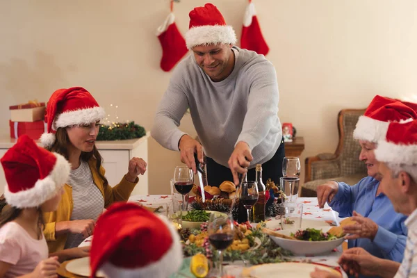 一代又一代的高加索人一家人一起坐在餐桌前吃饭 戴着桑塔帽 就是做饭的那个人 优质家庭时间圣诞庆祝活动 — 图库照片