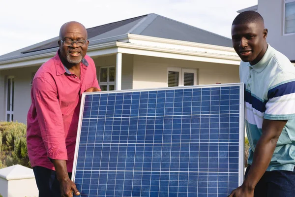 Afrykański Starszy Pan Synem Niosący Panel Słoneczny Stojący Podwórku Rodzina — Zdjęcie stockowe