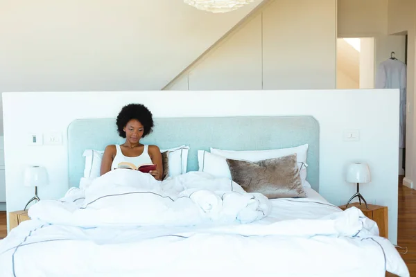 Afro Amerikalı Genç Bir Kadın Evdeki Rahat Yatakta Kitap Okuyor — Stok fotoğraf