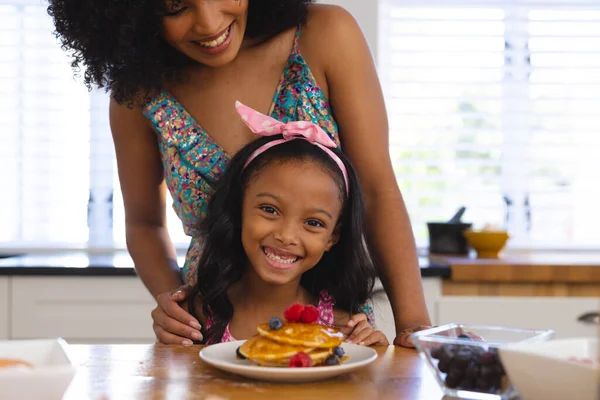 自宅でテーブルの上に魅力的なパンケーキと幸せな出産の母親と娘の中央部 肖像画 変更されていない 一緒に 子供時代 食べ物 ライフスタイルの概念 — ストック写真