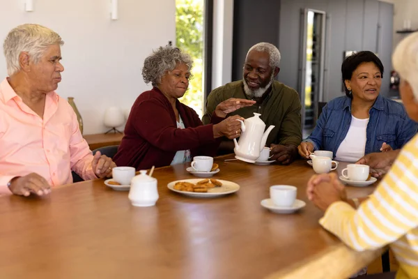在养老院的餐桌上 多种族的老朋友一边聊天 一边享用着饼干咖啡 不变的 辅助生活 — 图库照片
