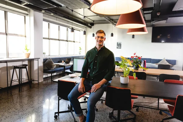 オフィスの机の上に座って笑顔若い白人ビジネスマンの肖像画 変化のない創造的なビジネス 前向きな感情 — ストック写真