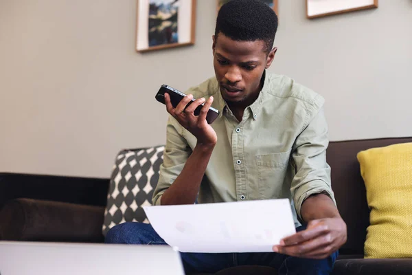 アフリカ系アメリカ人の若いビジネスマンがオフィスでスマートフォンスピーカーを通して話しています 変更されていない 創造的なビジネス 無線技術 ボイスメール 音声認識 — ストック写真