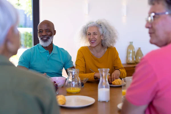 在养老院的饭桌边吃早餐的时候 多种族的老朋友聊得开心极了 辅助生活和退休概念 — 图库照片