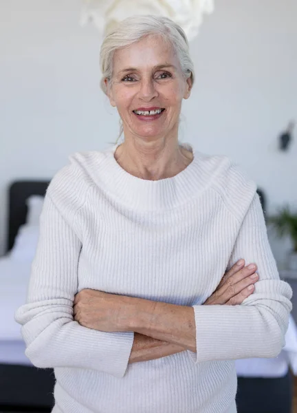 腕を持つ白人のシニア女性の肖像画は 自宅で寝室に立って笑みを浮かべて交差しました 定年退職者のライフスタイルと生活コンセプト — ストック写真