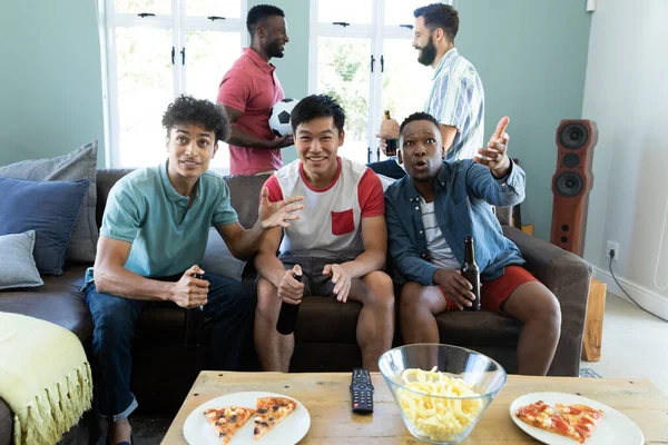 多种族的男性朋友坐在沙发上聊天 同时在家里观看足球比赛 社交活动 娱乐和周末活动概念 — 图库照片
