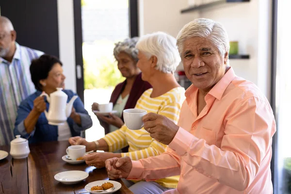 与多种族朋友一起在餐桌边喝咖啡和饼干的长大成人的画像 不变食品 帮助生活和退休之家 — 图库照片