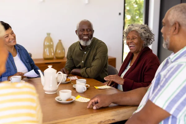 在养老院 多种族快乐的老朋友们 餐桌上放着宾果 咖啡和饼干 休闲游戏 不变的 辅助生活 — 图库照片