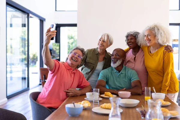 白种人老年人在饭桌上吃早餐的时候 与多种族朋友自私自利 辅助生活 — 图库照片