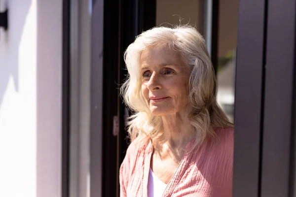 Biała Troskliwa Starsza Kobieta Falowanymi Włosami Patrząca Przez Okno Dom — Zdjęcie stockowe