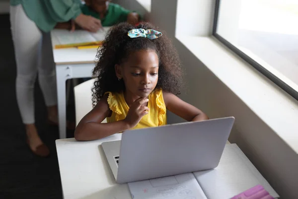 アフリカ系アメリカ人の小学生がパソコン教室の机でノートパソコンを使って授業をしています 変化のない教育子供時代学習無線技術学校の概念 — ストック写真