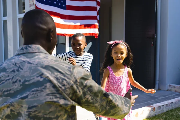 多种族兴奋的孩子们穿着迷彩服奔向军队的父亲 在院子里拥抱他 不变的 美国国旗 爱国主义 — 图库照片