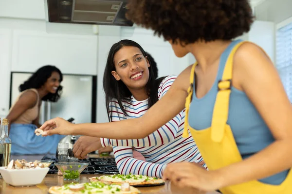 キッチン島のピザを自宅で調理しながら 友達を見ている出産の若い女性を笑顔 食べ物 変更されていない 社会的な集まり 楽しさと週末の活動の概念 — ストック写真