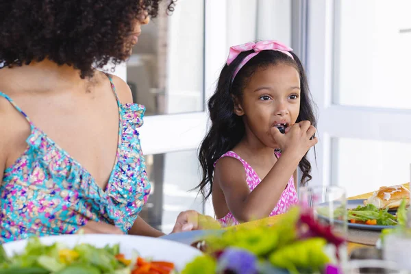 生小孩的女孩一边吃着食物 一边望着别处 一边和妈妈一起坐在餐桌边吃午饭 不变的家庭 生活方式和家庭观念 — 图库照片