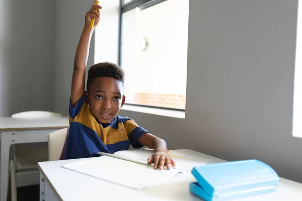 African American Elementary Schoolboy Hand Raised Sitting Desk Classroom Unaltered — Stock Photo, Image