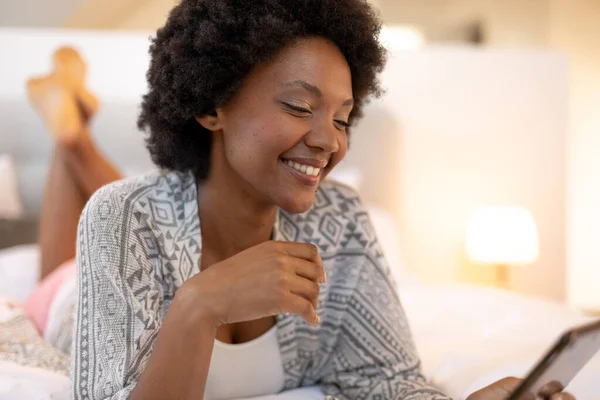 年轻的非洲裔美国妇女躺在卧室里用数字平板电脑微笑 复制空间 生活方式 家庭和技术概念不变 — 图库照片
