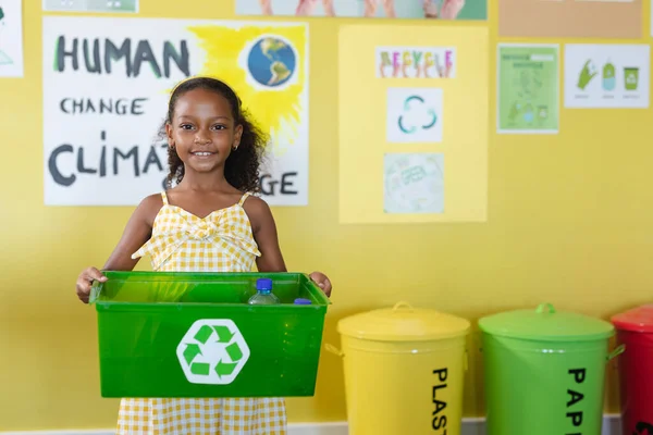 笑着的非洲裔美国小学生的画像 她拿着装有回收符号的容器 环境清理 可持续生活方式和学校概念 — 图库照片