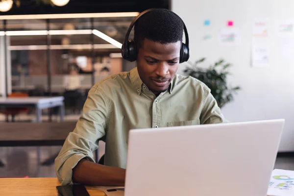 Αφροαμερικάνος Νεαρός Επιχειρηματίας Που Φοράει Ακουστικά Χρησιμοποιώντας Φορητό Υπολογιστή Στο — Φωτογραφία Αρχείου