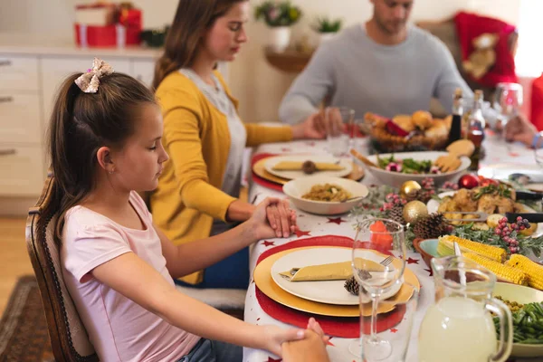 多代高加索人一家人坐在桌旁一起吃圣诞大餐 祈祷并牵着手 圣诞节家庭在一起的美好生活 — 图库照片