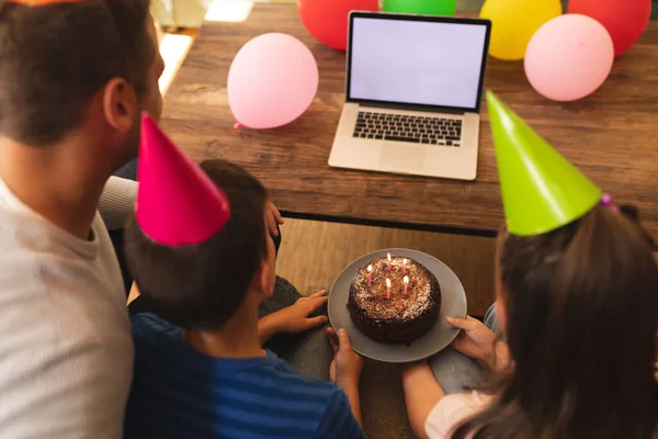 白人の家族は一緒に誕生日を祝い パーティーの帽子をかぶって ソファに座って ラップトップコンピュータを使って家で時間を過ごしています コロナウイルスの質の高い時間一緒にCovid 19隔離ロックダウン — ストック写真
