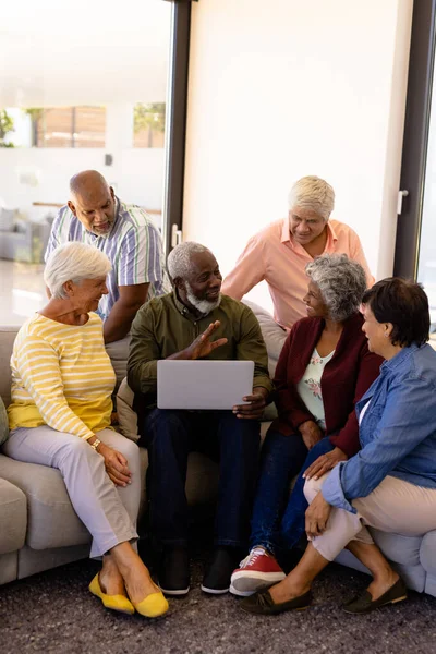 多种族老人坐在养老院的沙发上 一边和朋友们一边拿着笔记本电脑一边聊天 无线技术 辅助生活 退休概念 — 图库照片