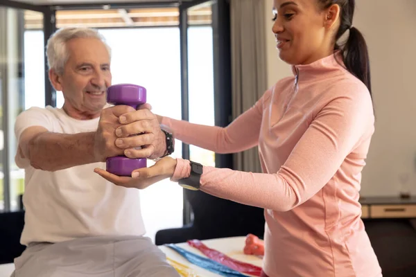 Smiling Biracial Female Physiotherapist Helping Caucasian Senior Man Lifting Dumbbell — Foto de Stock