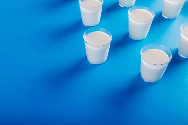 コピースペースのある青の背景に配置されたミルクグラスの高い角度ビュー 変更されていない 食べ物 飲み物 スタジオで撮影された健康的な食品コンセプト — ストック写真
