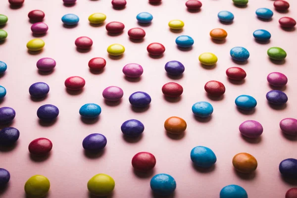 多色巧克力糖果的高角度全景 散布在粉色背景上 不变的 不健康的饮食和甜食概念 — 图库照片